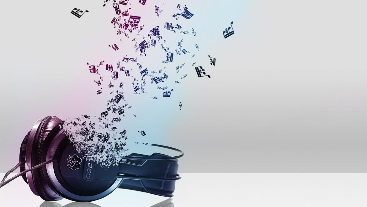 A pair of black headphones rests on a reflective surface, with colorful musical notes and symbols emerging and floating upward from the earcups against a light gray background.