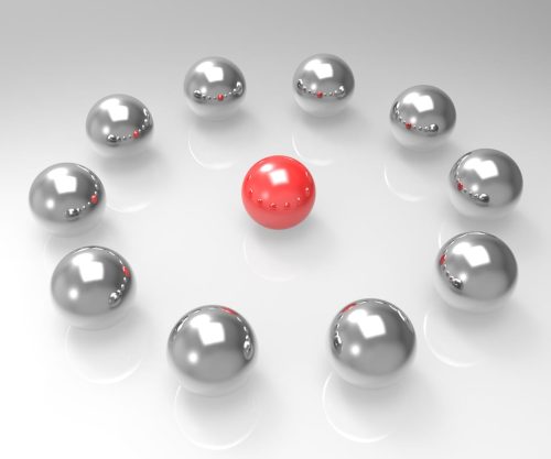 A group of ten shiny silver spheres arranged in a circle around a single red sphere at the center, all on a glossy white surface.