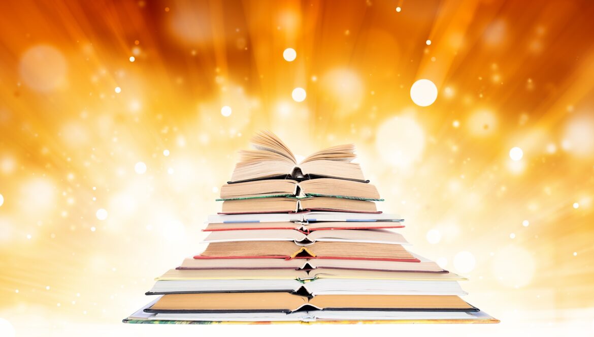 A pyramid of stacked books with an open book on top, set against a glowing, golden background with bokeh light effects.