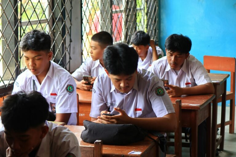 Students in uniform using phones in classroom