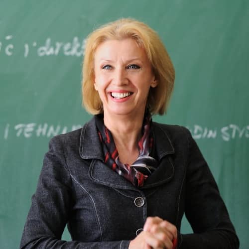 Teacher smiling in front of a chalkboard