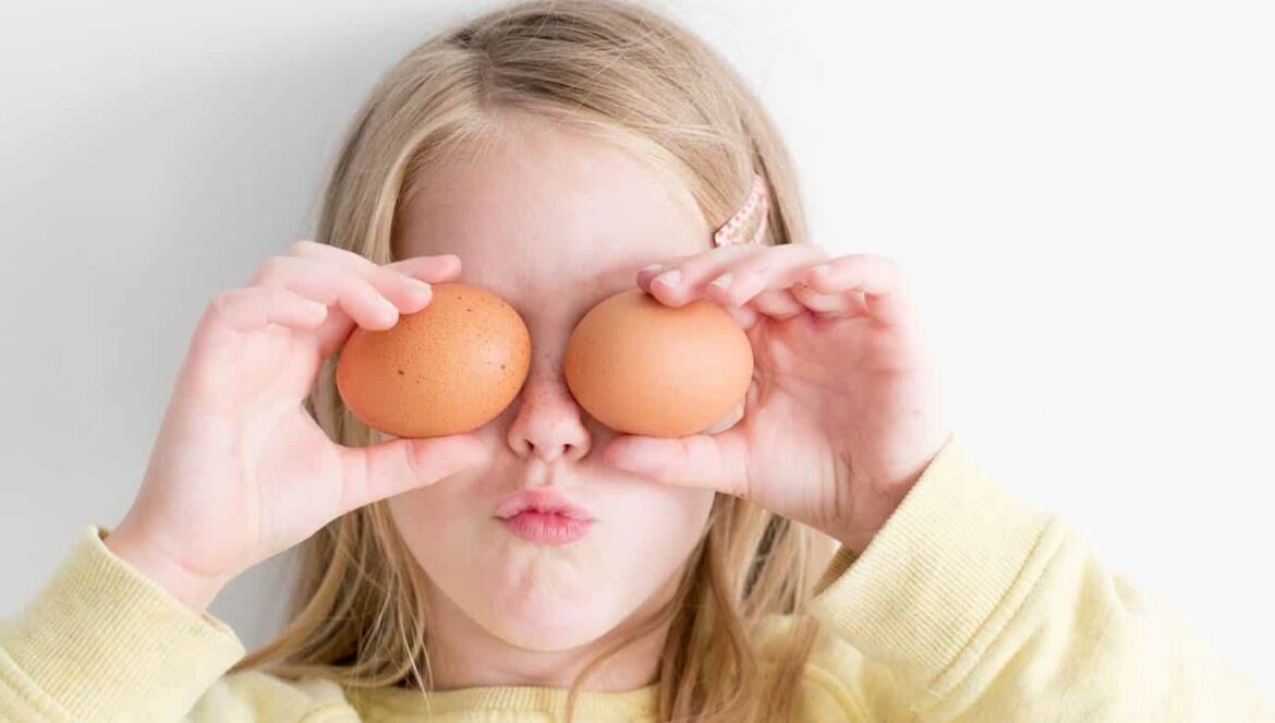 girl holding eggs up to cover her eyes