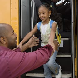 Mature man picking up his little daughter from school bus