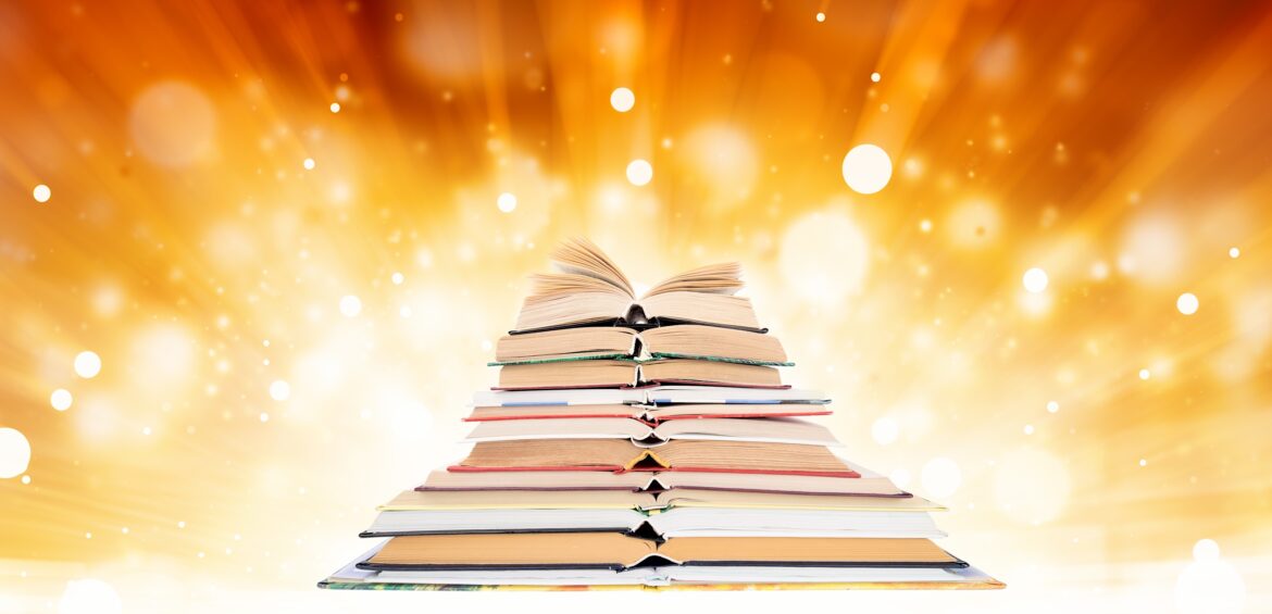 A pyramid of stacked books with an open book on top, set against a glowing, golden background with bokeh light effects.