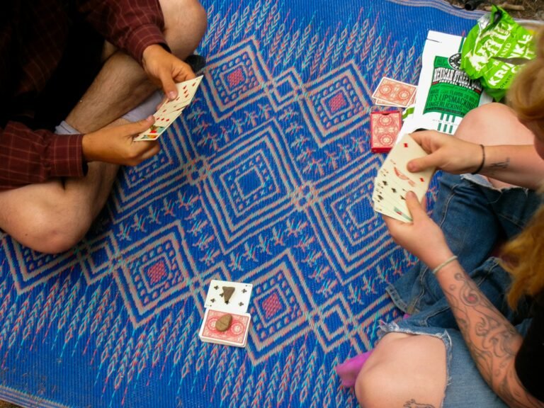 Two people playing cards on a blue patterned mat