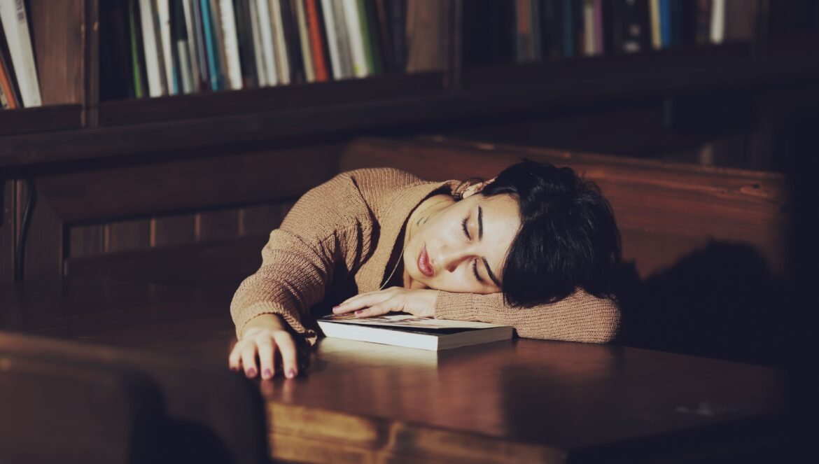 A woman with short hair sleeps on a table in a quiet library resting