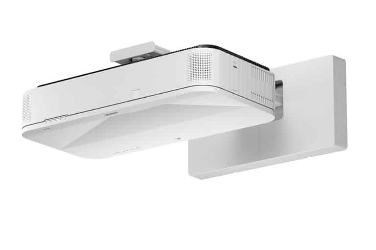 A modern white wall-mounted projector with a sleek, rectangular design and ventilation grilles, viewed from a low angle against a plain white background.