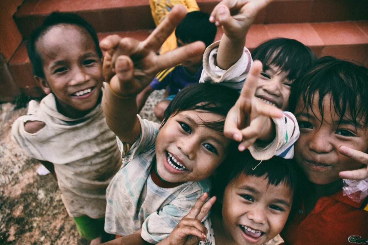 Five children smiling while doing peace hand sign