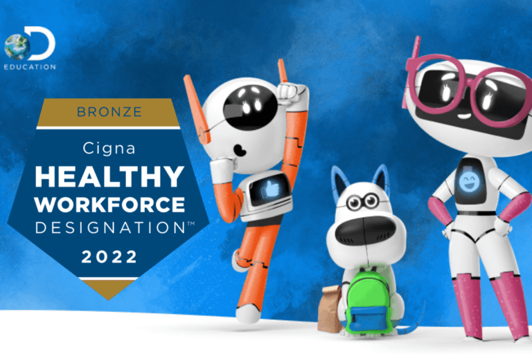 Three cheerful cartoon robots and a robot dog stand next to a blue badge that reads Bronze Cigna Healthy Workforce Designation 2022 on a blue background with the Discovery Education logo in the corner.