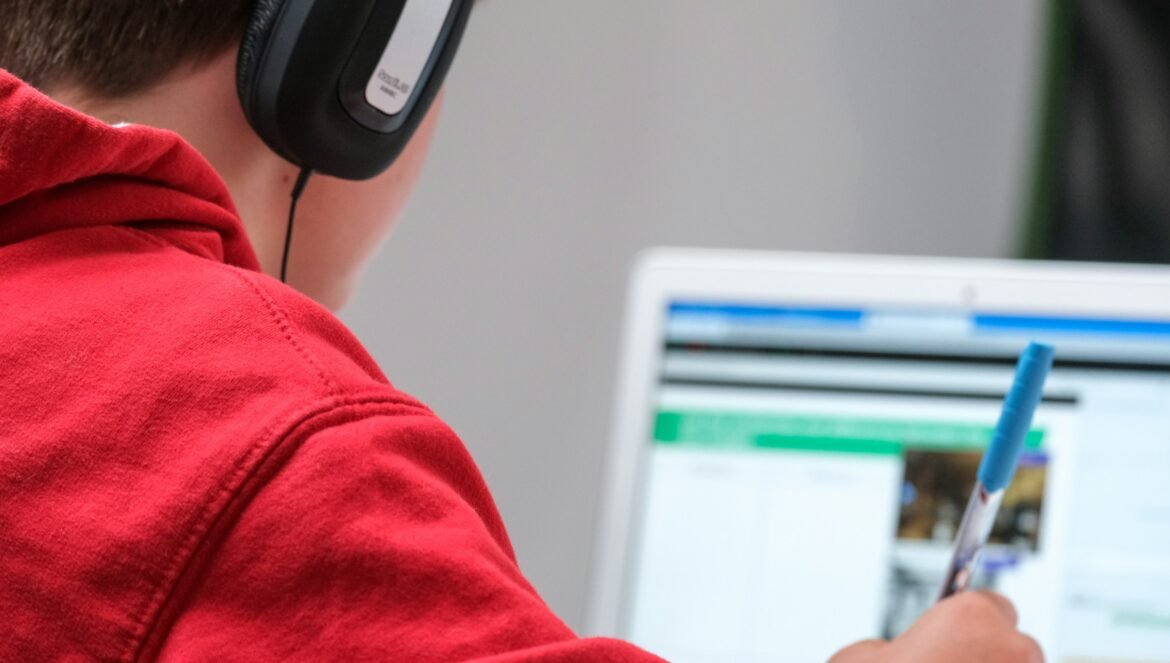 Person in red shirt wearing black and gray headphones | edCircuit Person in red shirt wearing black and gray headphones