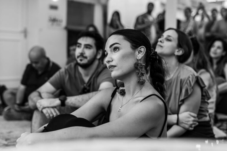 A group of adults attentively sitting indoors, captured in a black and