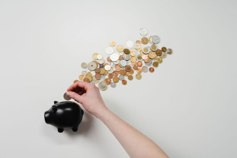 Person placing coin into a black piggy bank with scattered coins, symb