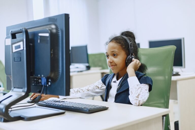 Smiling girl using computer in a modern lab setting, wearing a headset
