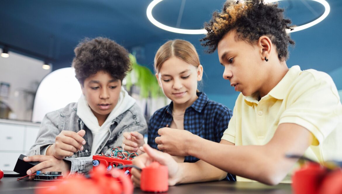 Diverse teenagers collaboratively working on a robotics project in a w