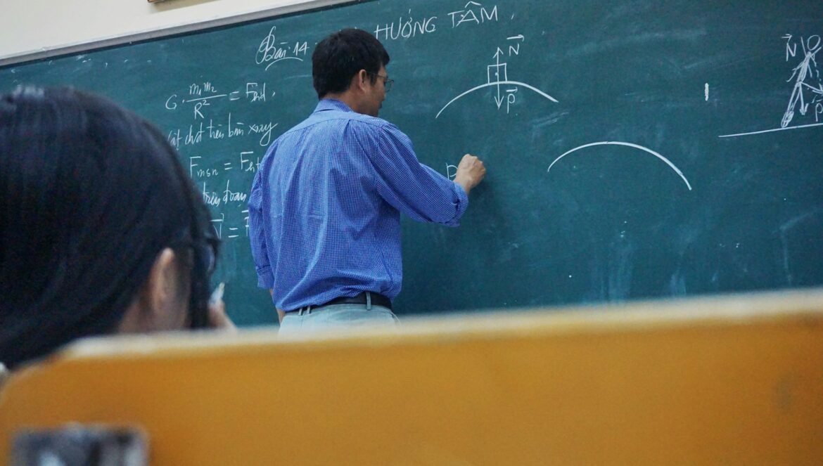 A teacher writing physics equations on a green chalkboard in a classro | edCircuit A teacher writing physics equations on a green chalkboard in a classro