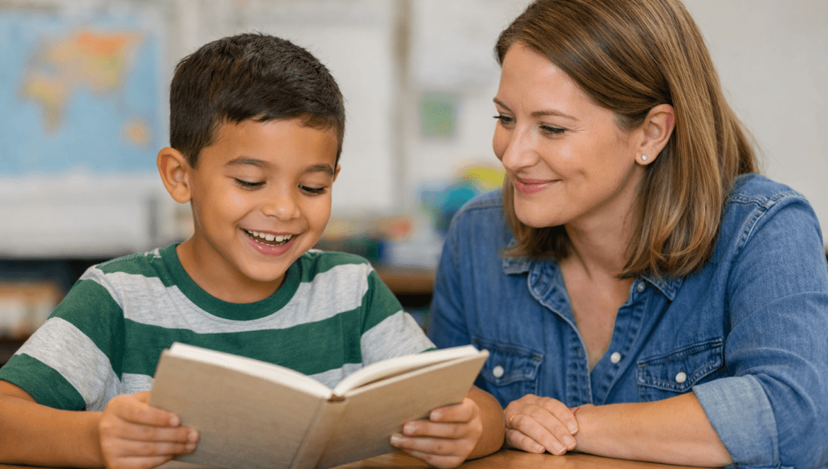 A young boy in a striped shirt reads a book at a desk while a smiling woman sits beside him, encouraging him with methods from the science of reading. The background is a classroom with blurred maps and a whiteboard.