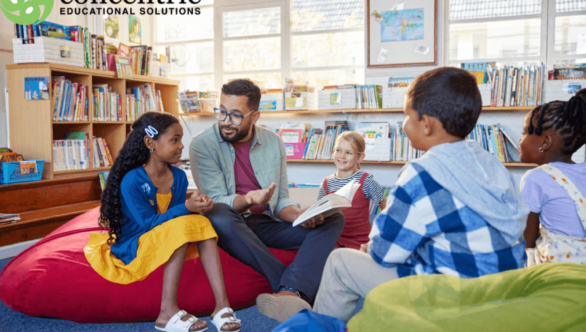 A teacher sits on a bean bag with four young students in a library, engaging them in a discussion. The Concentric Educational Solutions logo appears in the top left corner.
