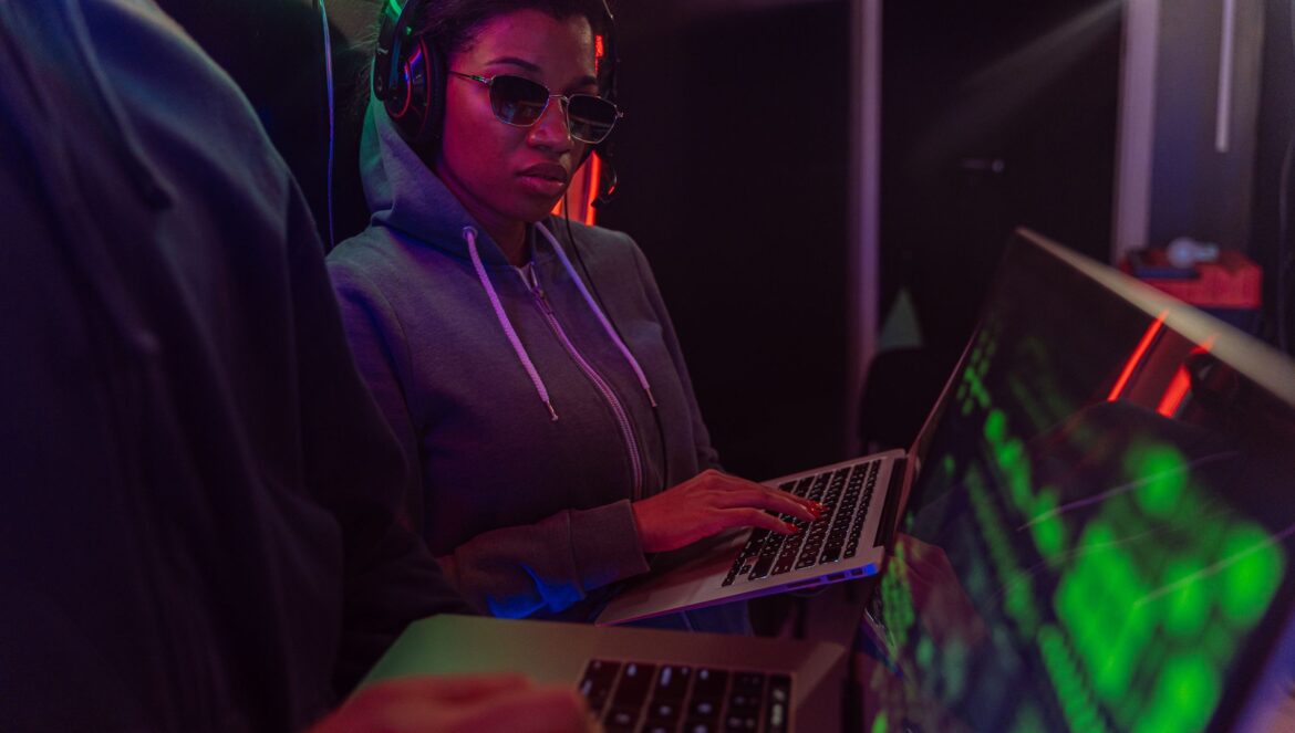 A tech savvy adult using a laptop at night with neon lighting creatin