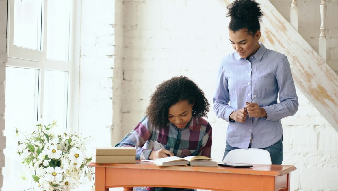 Woman helps girl with homework at desk