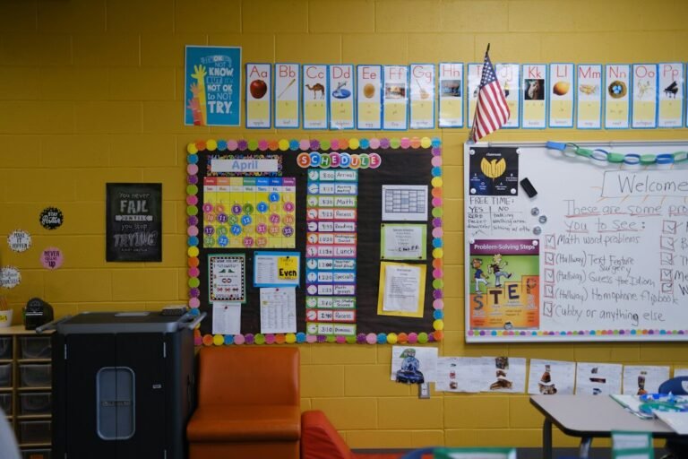 A classroom wall with a schedule, calendar, and alphabet posters on yellow brick