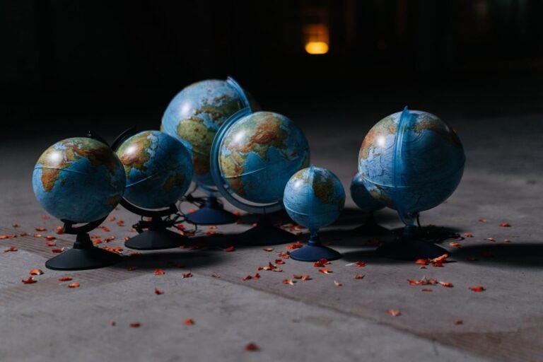 A collection of globes arranged on a concrete floor, surrounded by scattered petals