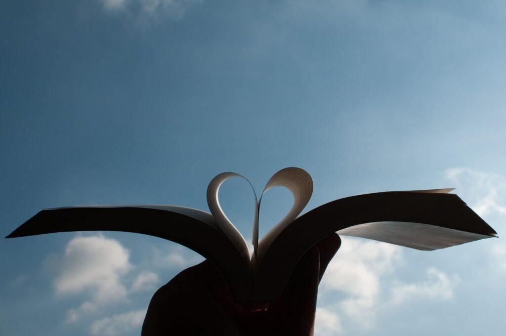 A heart shape formed by an open books pages with a clear blue sky background in Milano Italy