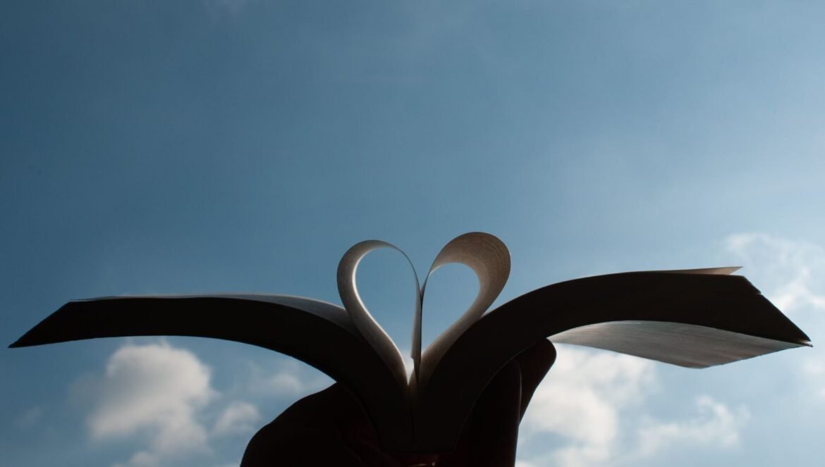 A heart shape formed by an open books pages with a clear blue sky background in Milano Italy