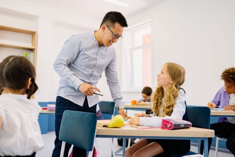 A male teacher interacting with diverse students in a bright classroom setting, promoting