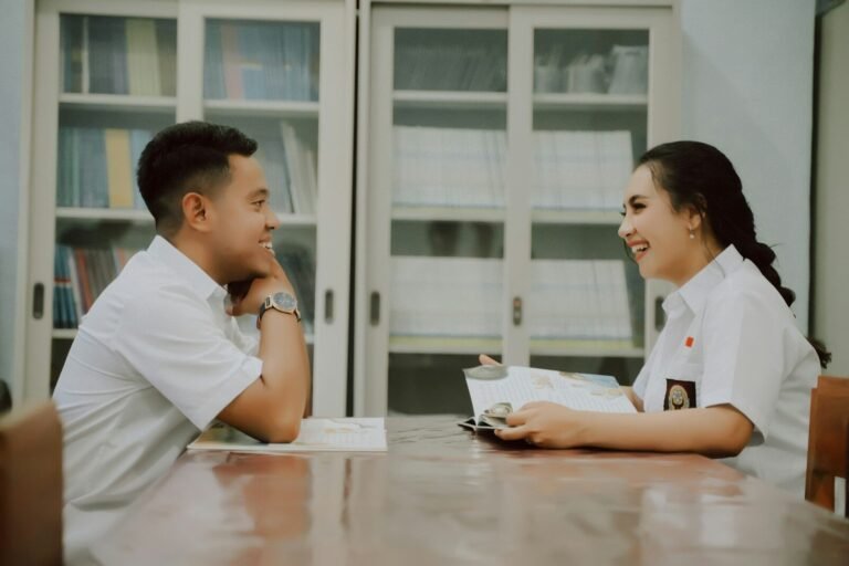 A man and a woman sitting at a table looking at a computer