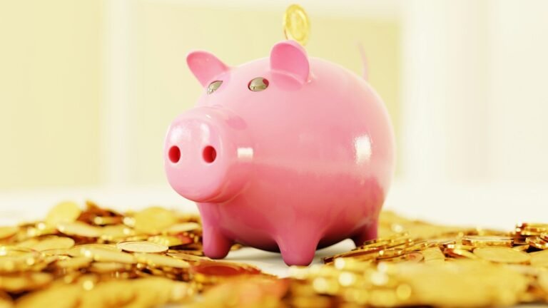 A pink piggy bank surrounded by a pile of gold coins