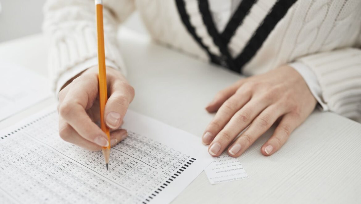 A student writing answers on a multiplechoice exam sheet at a desk | edCircuit A student writing answers on a multiple choice exam sheet at a desk