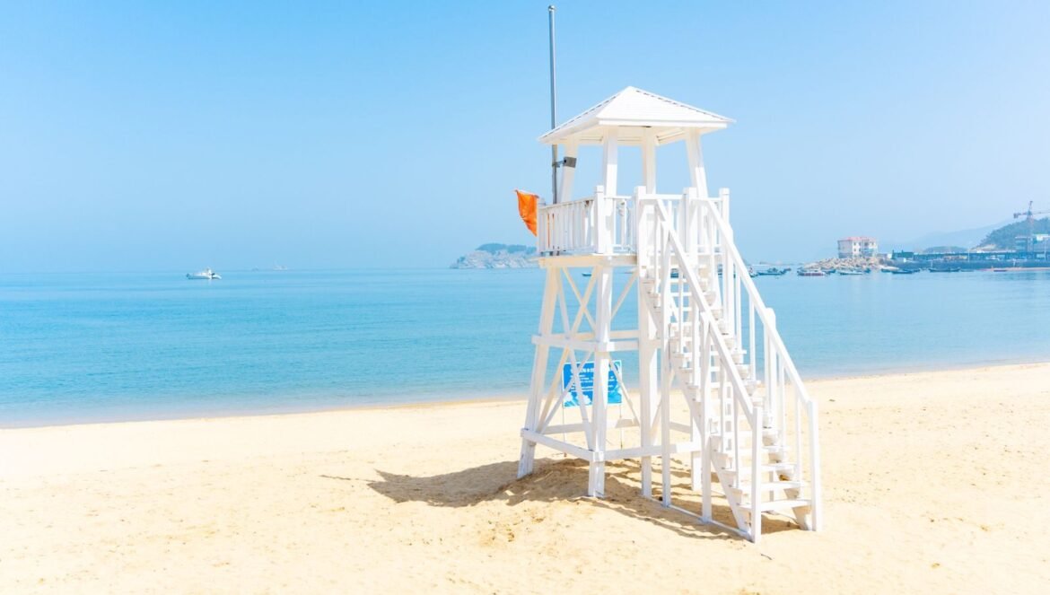 A tranquil beach scene featuring a white lifeguard tower clear water and blue