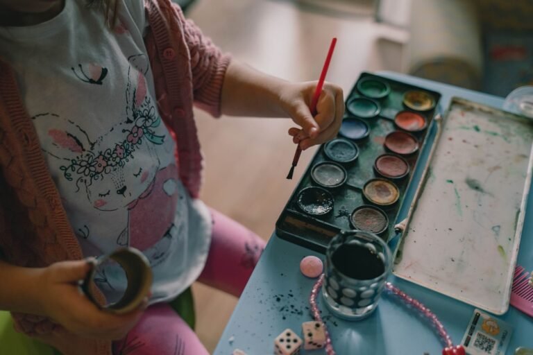 A young child painting with watercolors, wearing a cute printed shirt, engaging