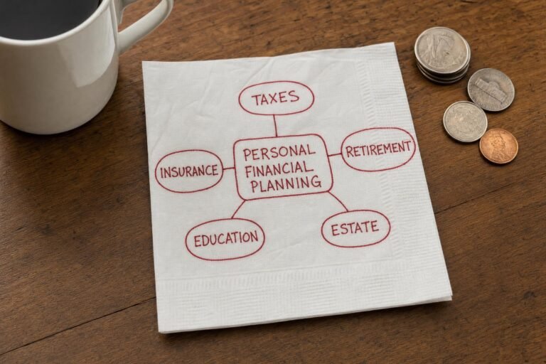 A paper napkin on a wooden table with a hand-drawn mind map in red ink linking PERSONAL FINANCIAL PLANNING to TAXES, INSURANCE, RETIREMENT, EDUCATION and ESTATE