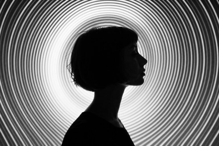 A person's silhouette in profile against a background of concentric curved white light lines radiating from the head