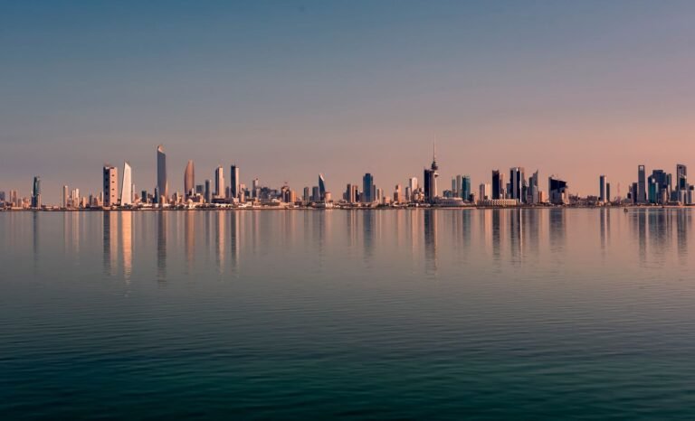 Beautiful Kuwait City skyline reflected on calm water at sunset, showcasing mode