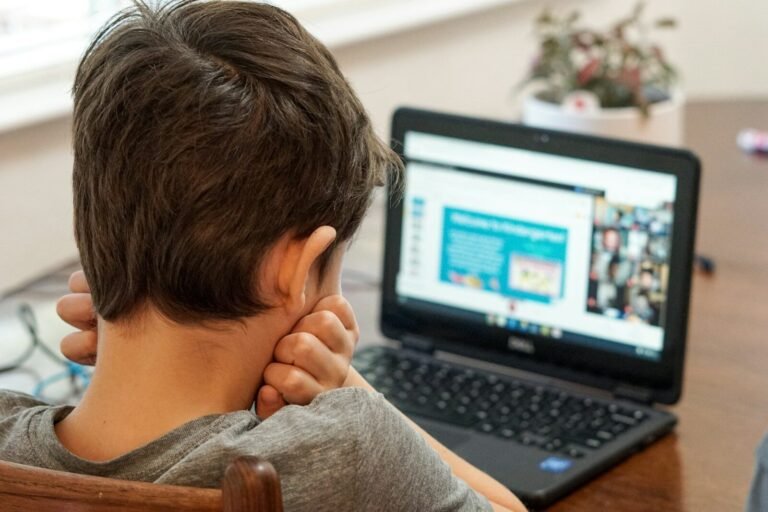 Boy in gray shirt using black laptop computer