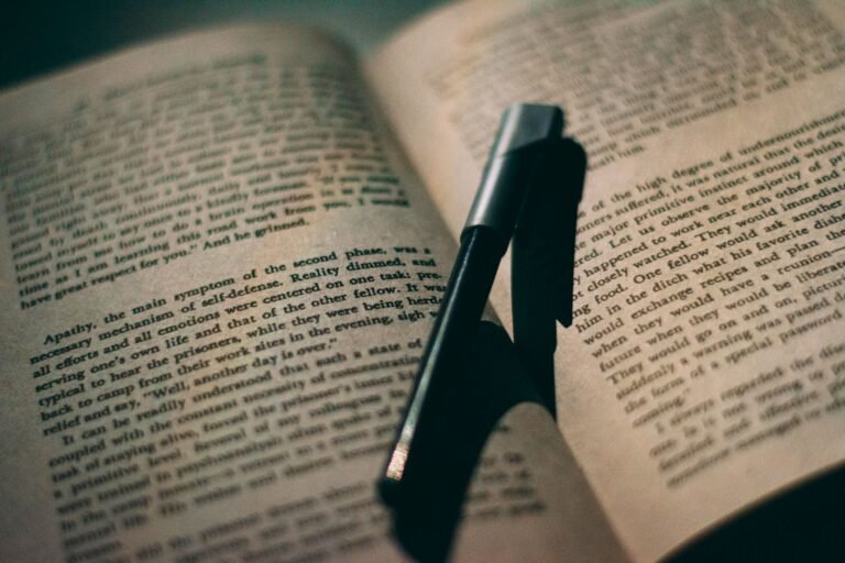 Close-up of a ballpoint pen resting between the pages of an open book, perfect for education or reading themes