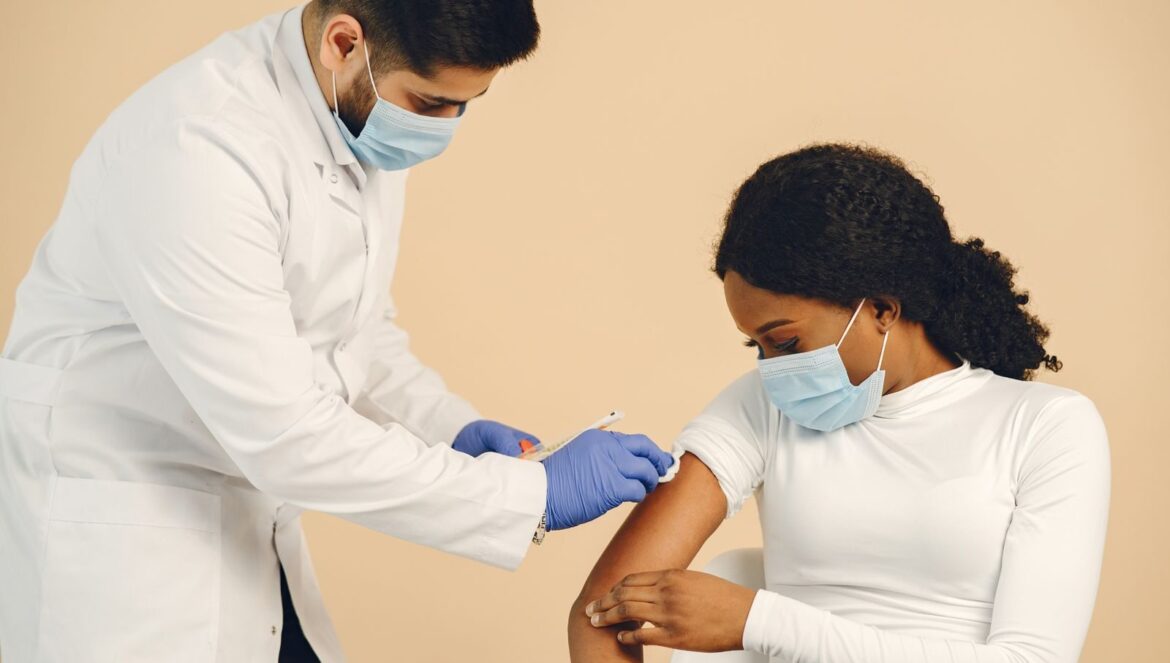 Close up of a healthcare worker giving a vaccine injection to a woman wearing a face mask