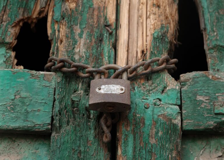 Close-up of a vintage green door with a rusty padlock and chain in Egypt