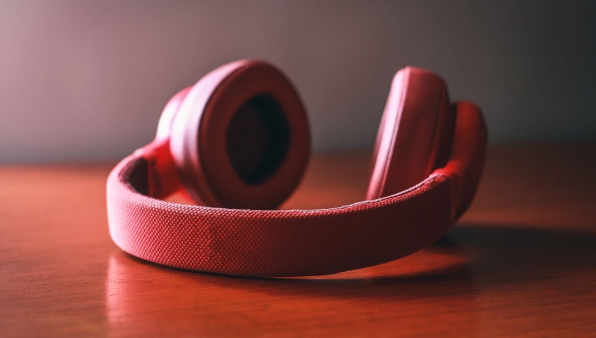 Closeup of vibrant red wireless headphones resting on a wooden surface | edCircuit Close up of vibrant red wireless headphones resting on a wooden surface