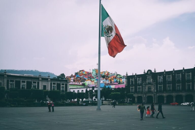 Colorful cityscape of Toluca with large Mexican flag in the foreground, vibrant buildings in the backdrop
