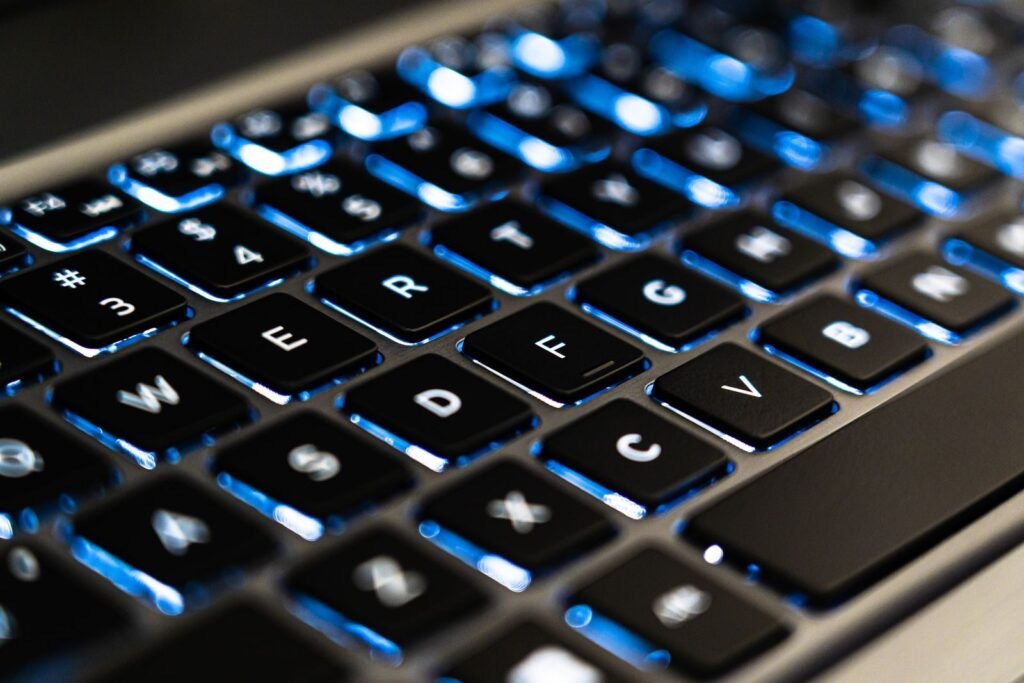 Detailed view of a backlit laptop keyboard keys with blue LED lighting for tech concepts