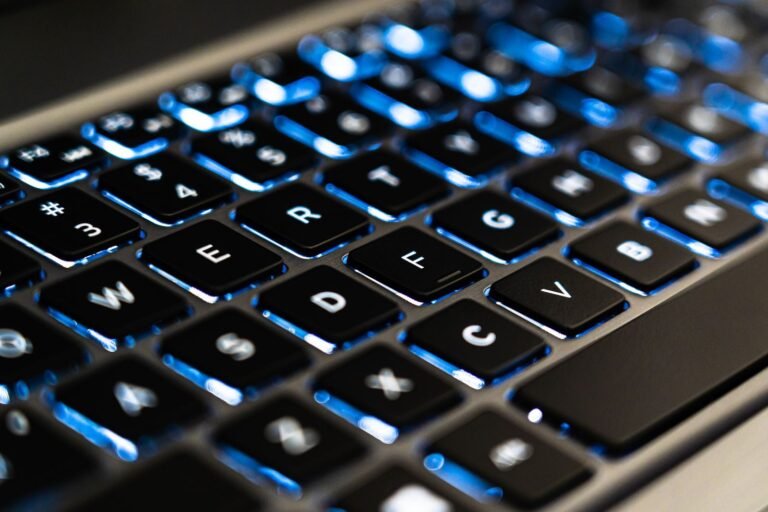 Detailed view of a backlit laptop keyboard keys with blue LED lighting for tech concepts