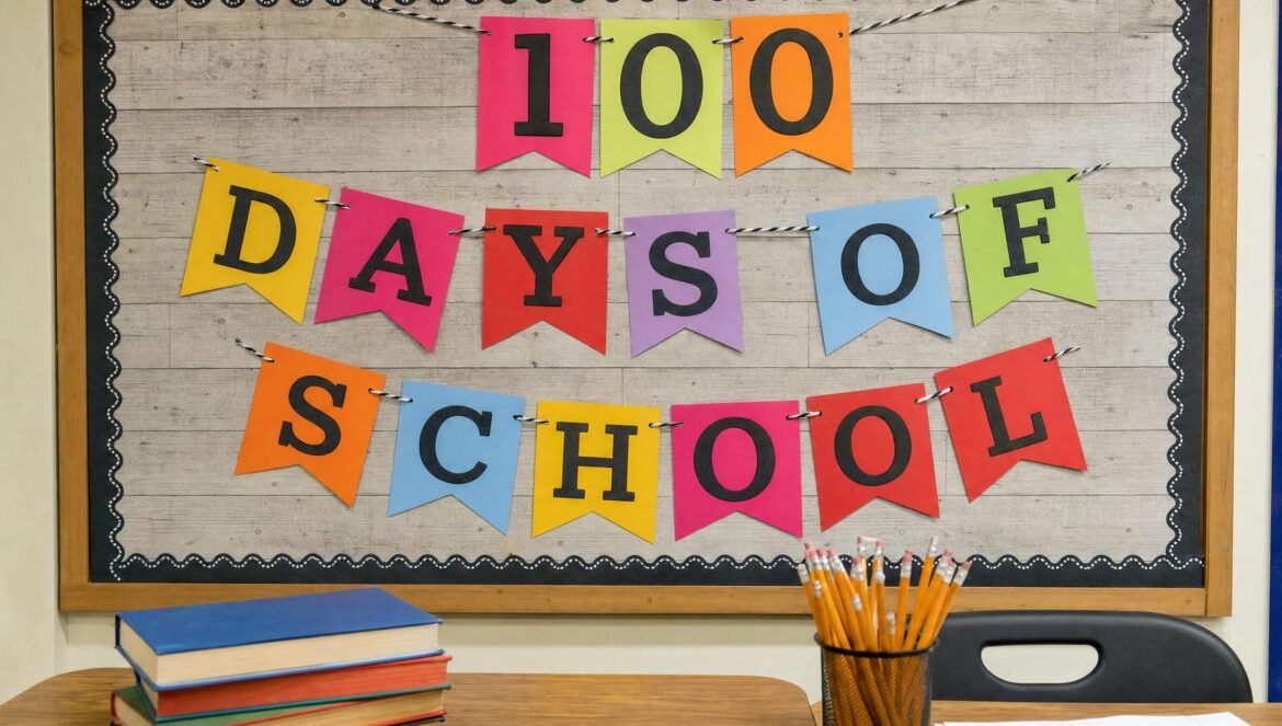 A cheerful elementary classroom bulletin board with colorful paper pennants and a sign reading 100 DAYS OF SCHOOL pencils and books on a desk in front