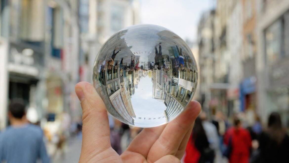 A clear glass crystal ball held up on a city shopping street the street and buildings appearing upside down inside it background softly blurred daylight | edCircuit A clear glass crystal ball held up on a city shopping street the street and buildings appearing upside down inside it background softly blurred daylight