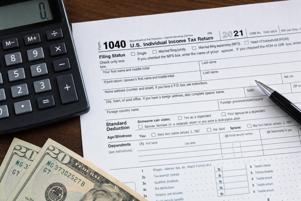 A printed tax return form on a desk beside a calculator a pen and a few dollar bills closeup soft light | edCircuit A printed tax return form on a desk beside a calculator a pen and a few dollar bills close up soft light