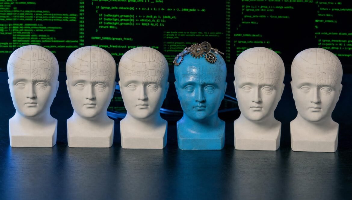A row of white plaster head busts on a dark desk one painted bright blue with small metal gears placed on its crown lit by cool blue light against a backdrop