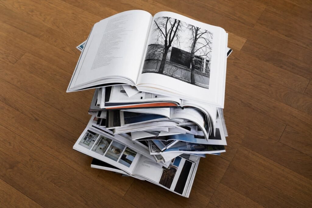 A tall messy stack of open books and magazines seen from above on a wooden floor bright even light | edCircuit A tall messy stack of open books and magazines seen from above on a wooden floor bright even light