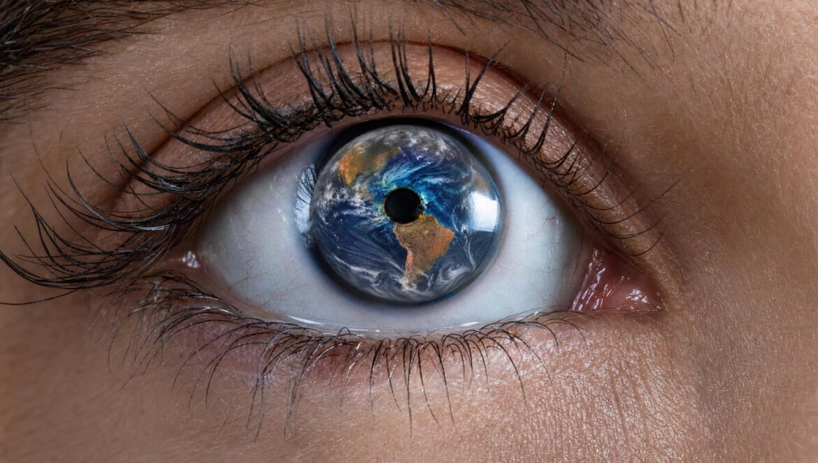 An extreme close up of a human eye whose iris reflects a blue and orange globe of the Earth long dark lashes crisp studio light